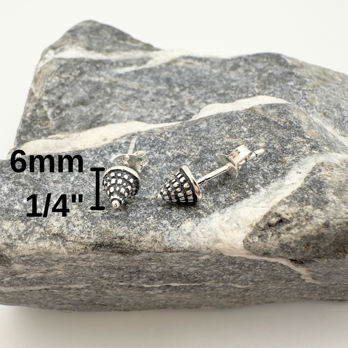Pair of silver stud earrings on a rock with measurements displayed.