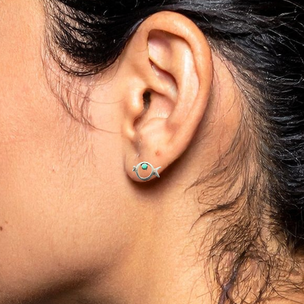 Close-up of an ear wearing a small earring with a dark background