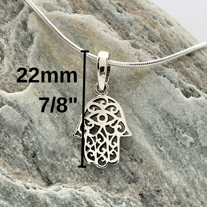 Silver Hamsa pendant with measurements on a stone surface