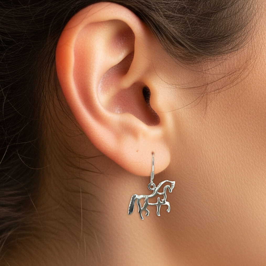 Close-up of an ear wearing a silver unicorn earring with a blurred background