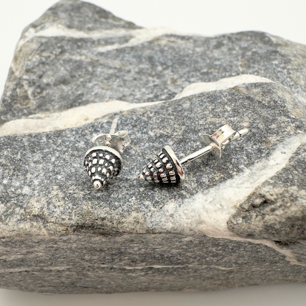 Silver stud earrings on a piece of gray stone