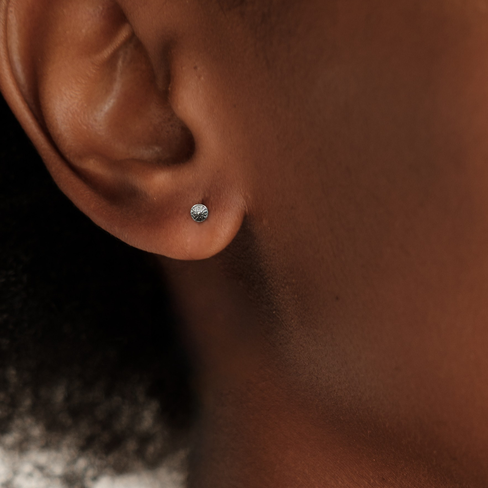 Close-up of an ear with a small earring on a neutral background