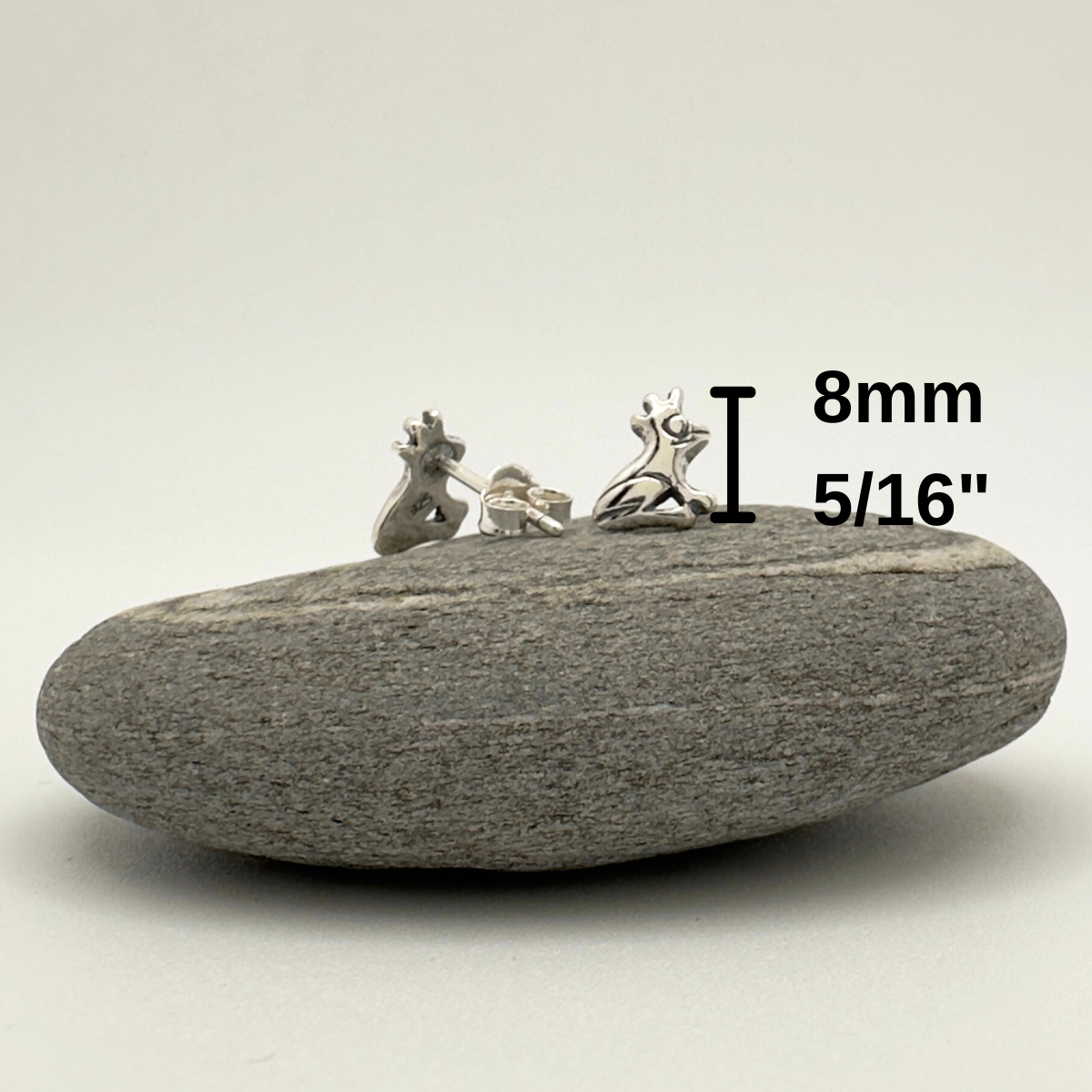 Small earrings on a stone with measurement text