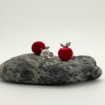 Red and silver earrings on a gray stone with a white background
