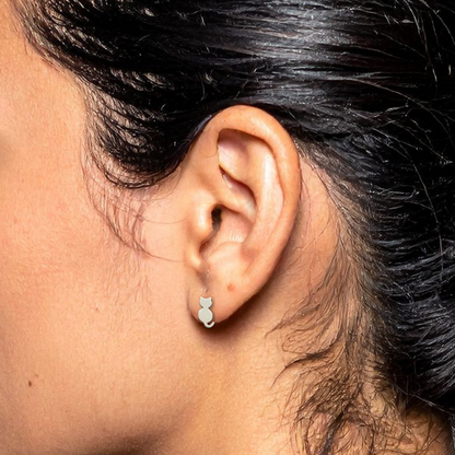 Close-up of an ear wearing a small earring with dark hair and blurred background