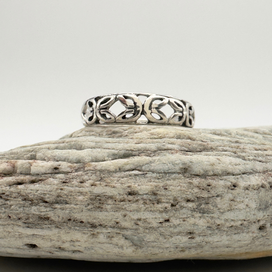 Silver ring with intricate design on a textured stone surface