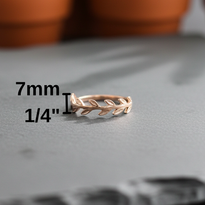 Rose gold ring with leaf design on a gray surface, measurement text overlay.