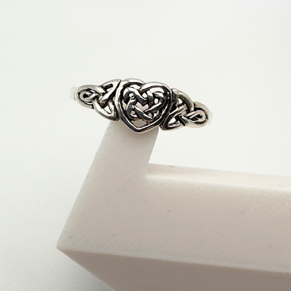 Silver ring with intricate design on a white surface