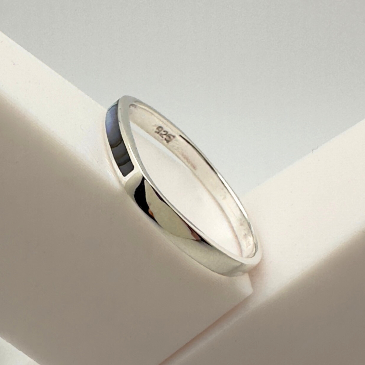 Silver ring on a white surface with a light gray background