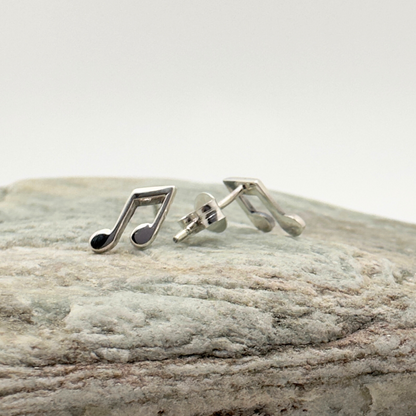 Silver music note earrings on a stone surface
