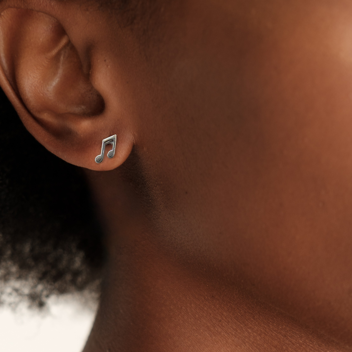 Close-up of an ear wearing a music note earring with a blurred background