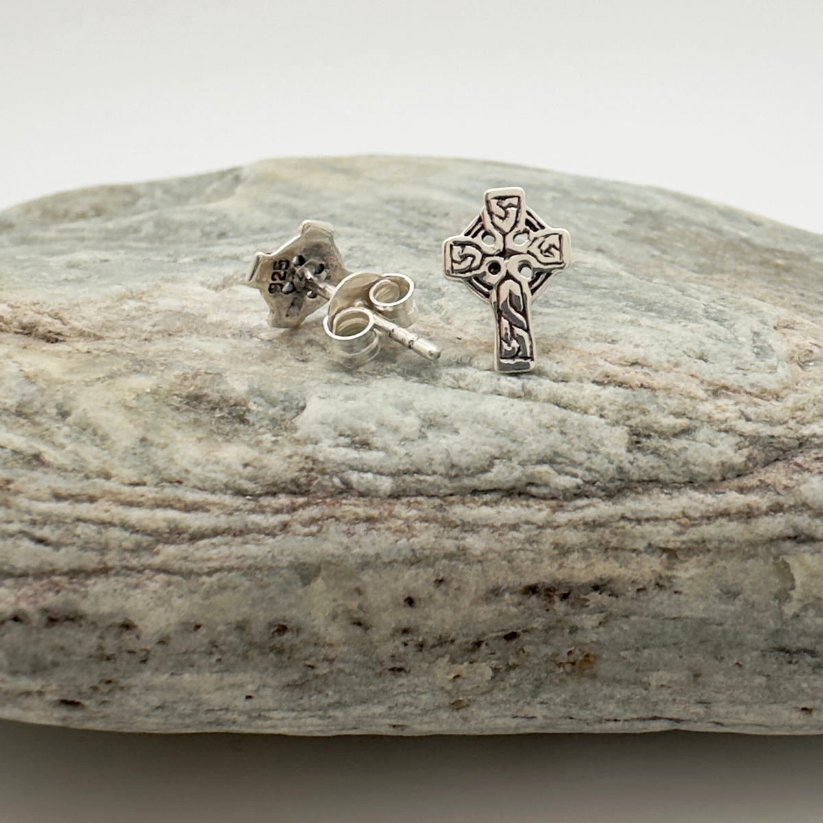 Silver cross earrings on a stone surface