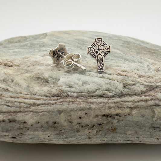 Silver cross earrings on a stone surface