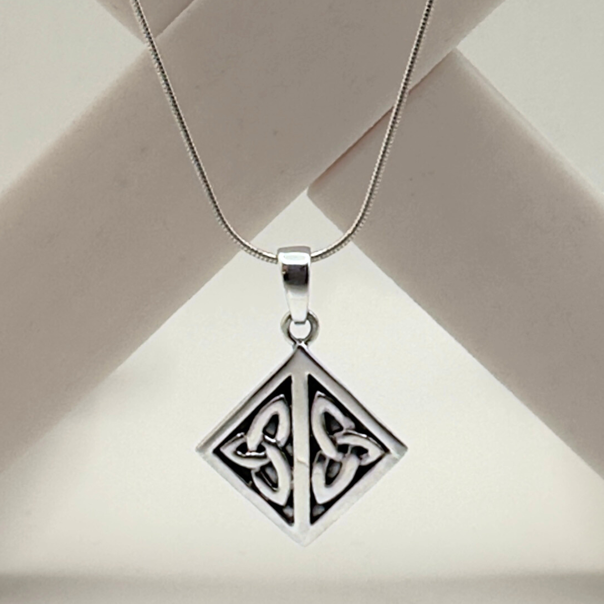 Silver pendant with Celtic design on a beige background