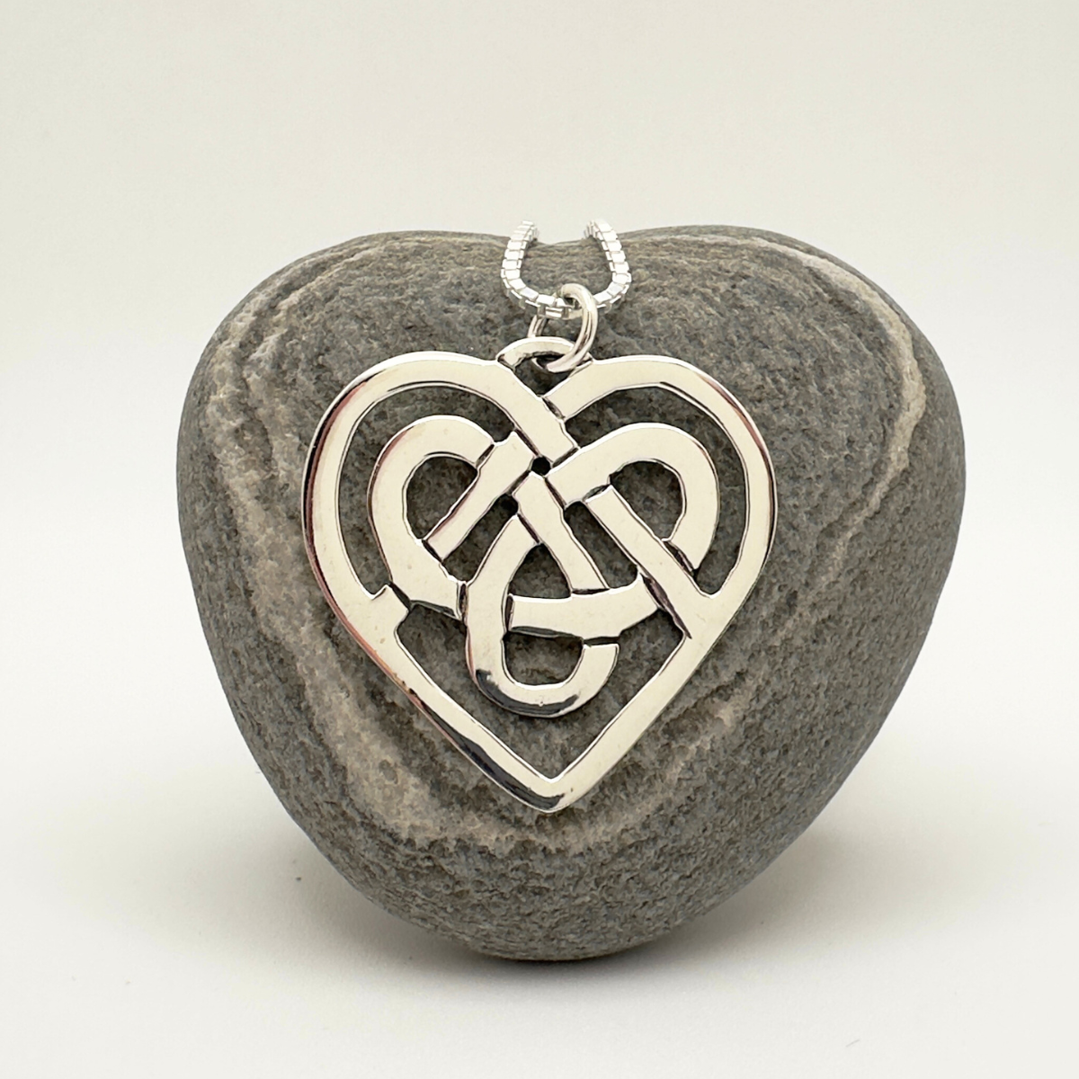 Silver Celtic knot heart pendant on a stone background