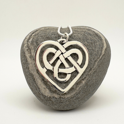 Silver Celtic knot heart pendant on a stone background