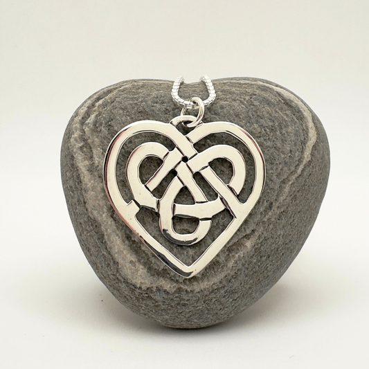 Silver Celtic knot heart pendant on a stone background