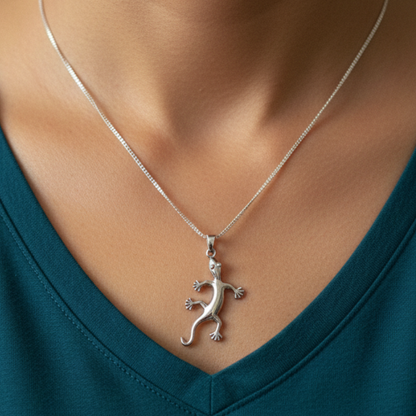 Silver lizard pendant necklace on a person wearing a teal top