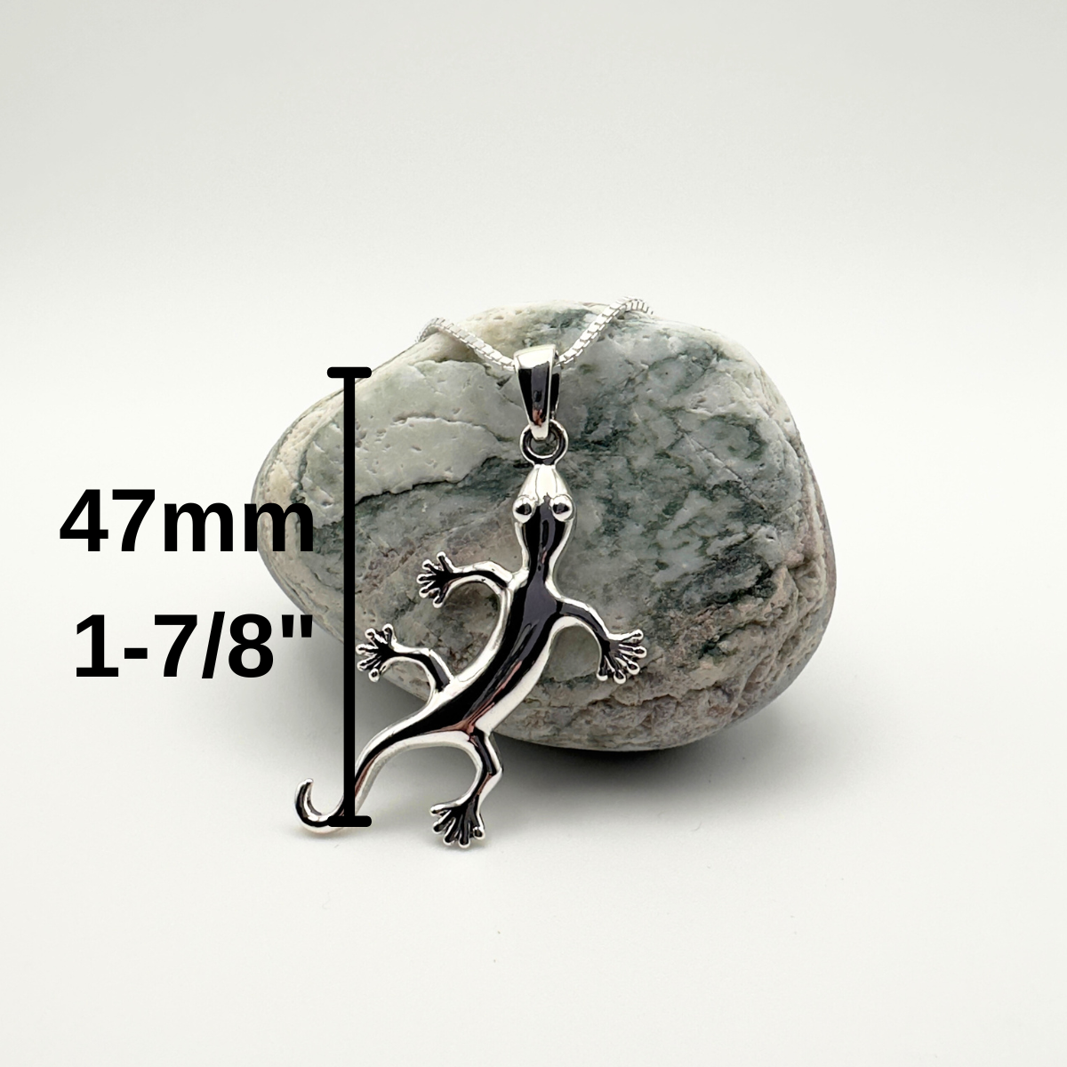 Silver lizard pendant on a rock with measurement text