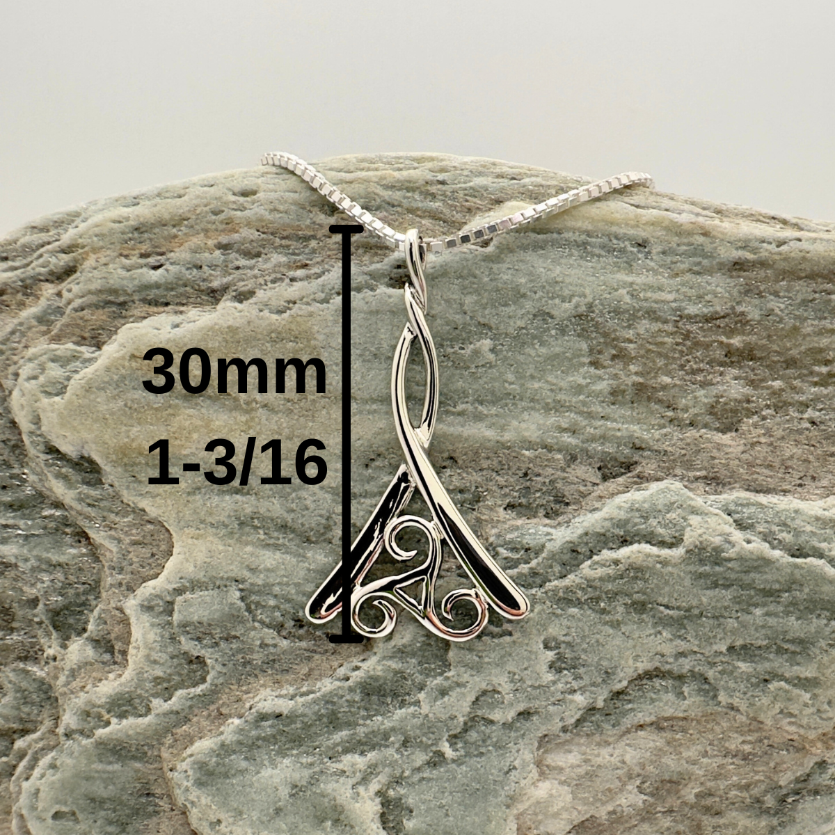 Silver pendant on a rock with measurement details