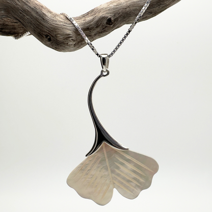 Necklace with a ginkgo leaf pendant on a branch against a white background