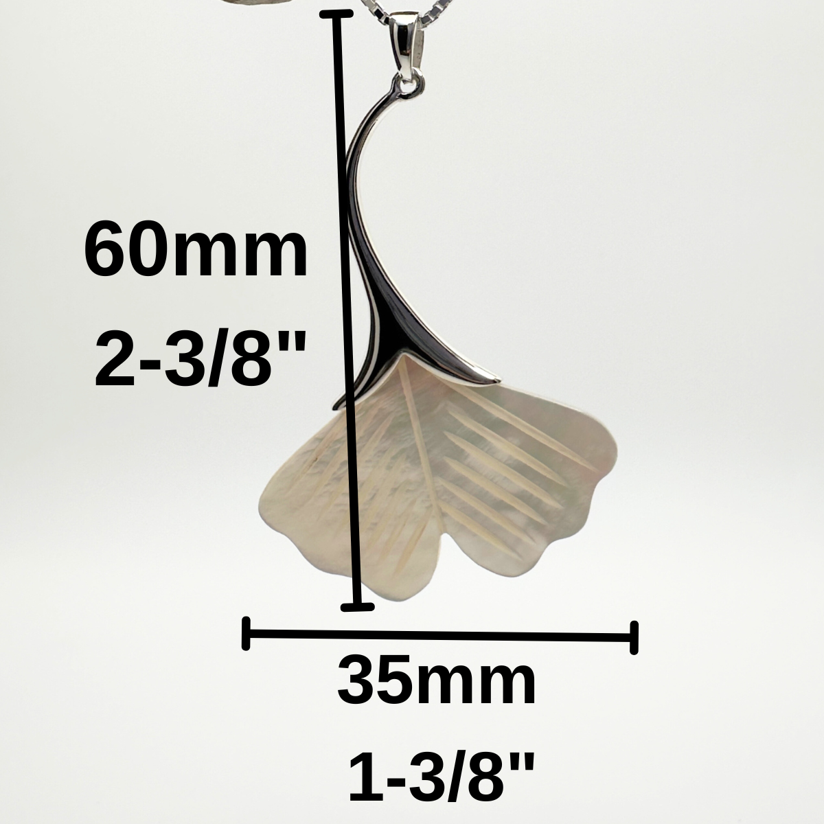 Silver leaf-shaped pendant on a branch with measurements indicated