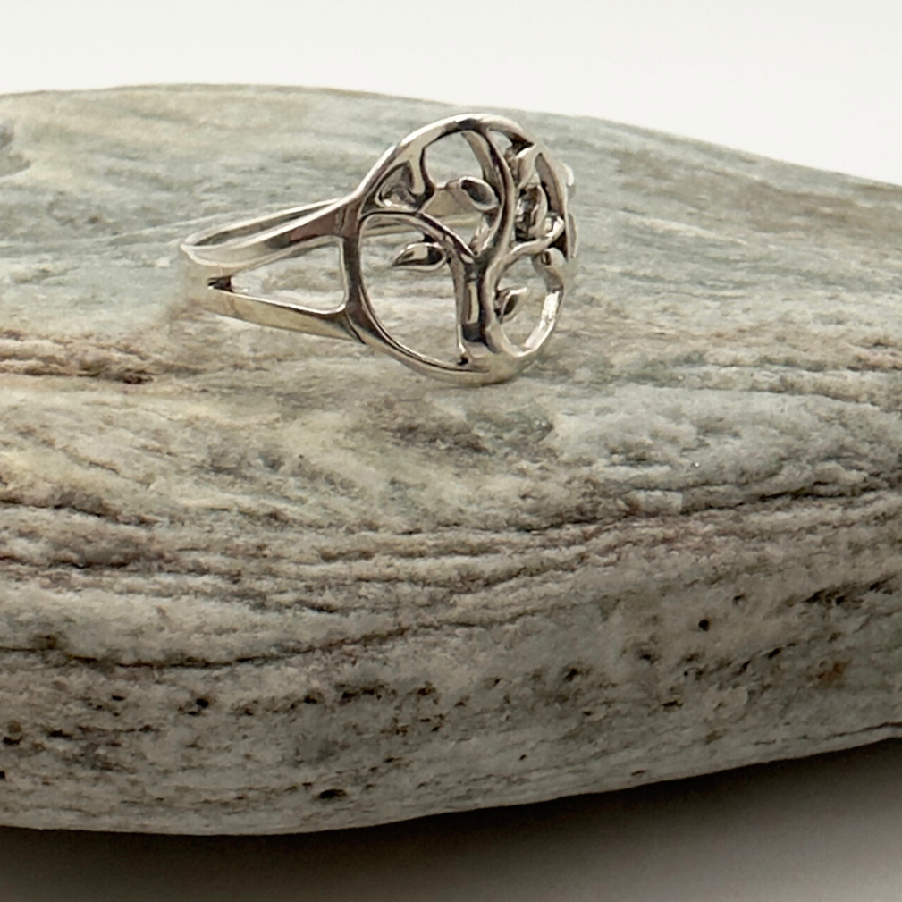 Silver ring with a tree design on a gray stone surface