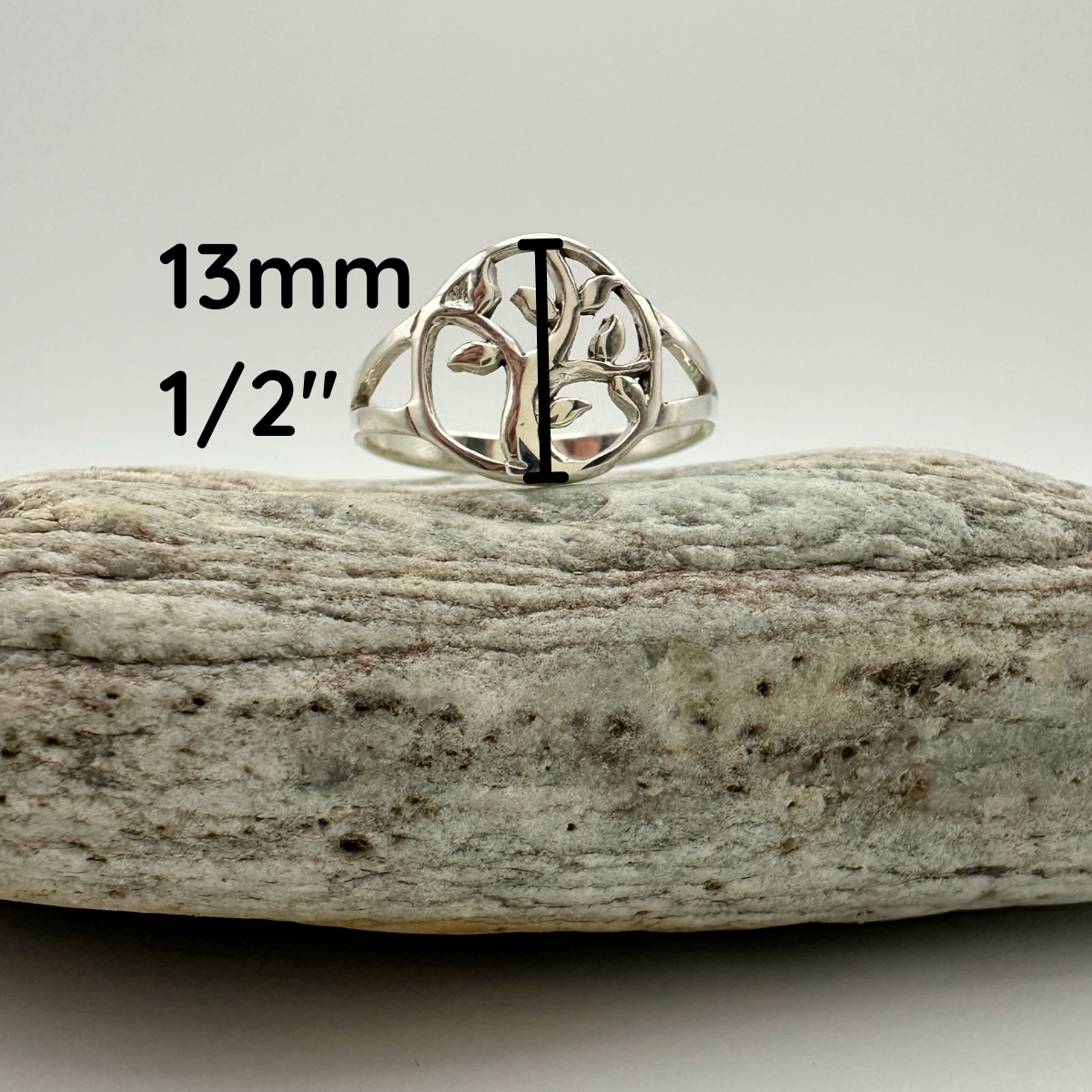 Silver tree-of-life ring on a rock with measurements displayed