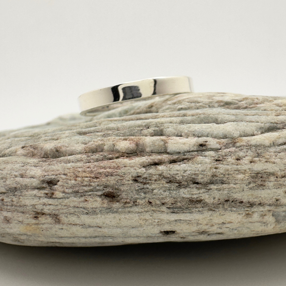 Silver ring on a textured stone surface with a white background