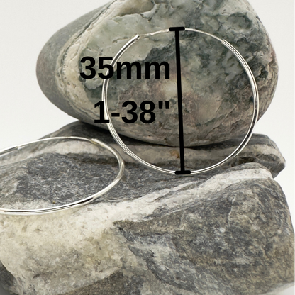 Two silver hoop earrings on a rock with measurement text