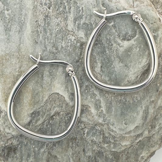 Silver hoop earrings on a textured stone surface