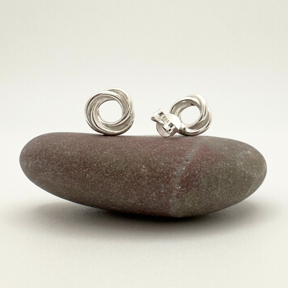 Silver earrings on a smooth stone with a plain background
