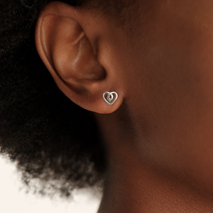Heart-shaped earring worn by a person with a neutral background