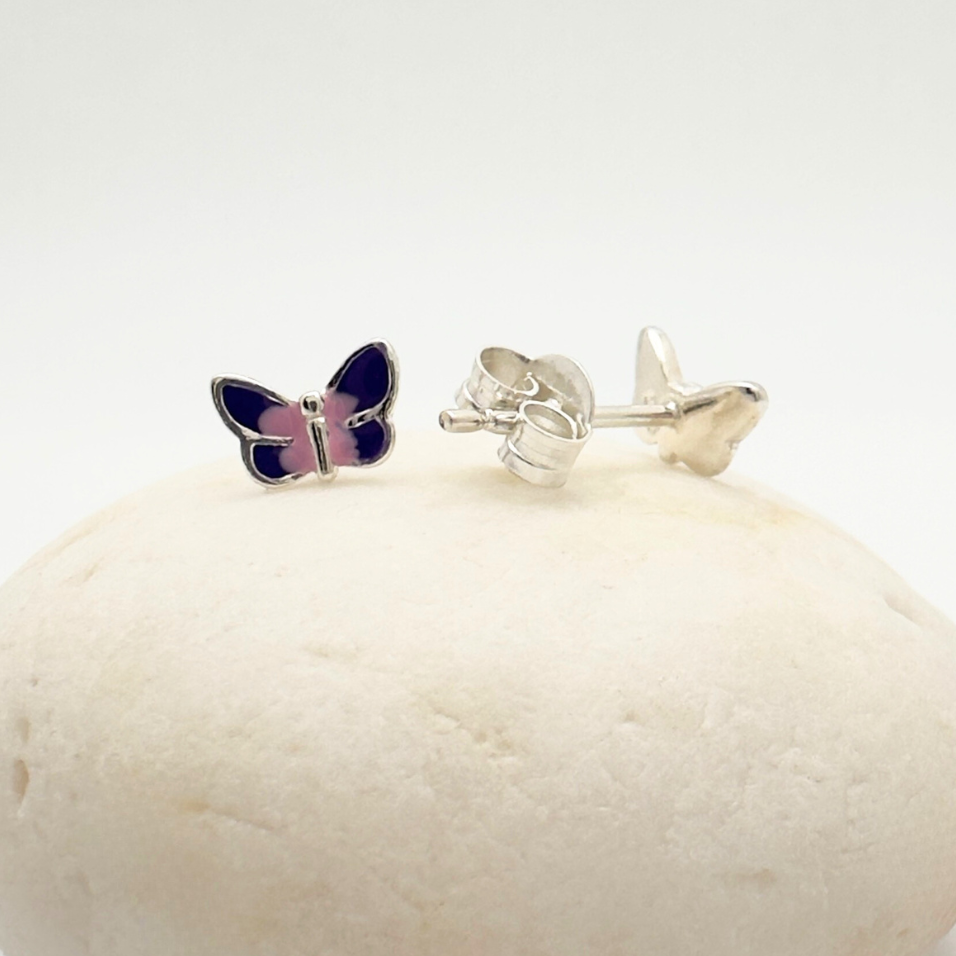 Butterfly-shaped earrings on a white stone with a white background