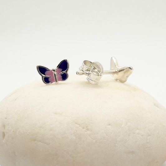 Butterfly-shaped earrings on a white stone with a white background