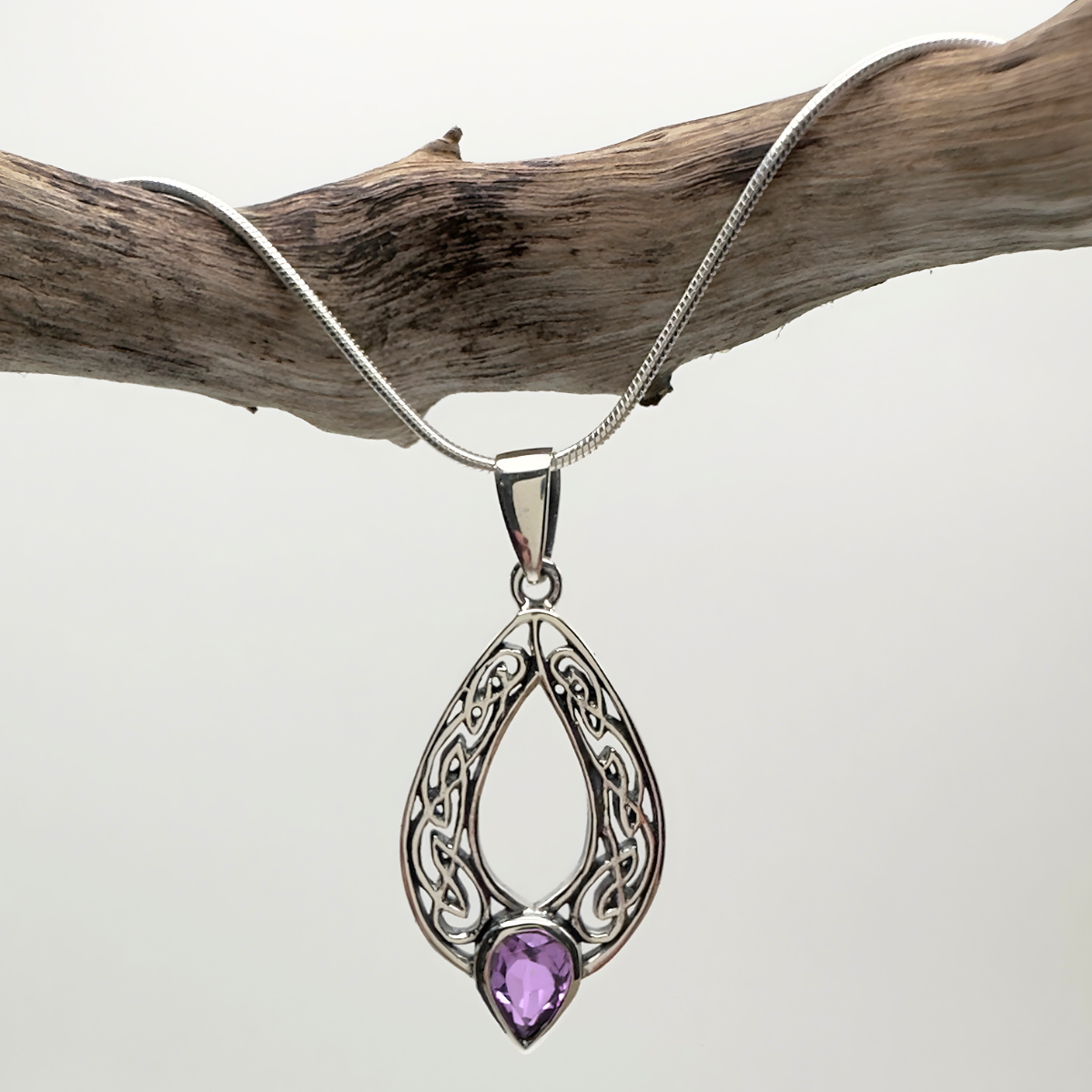 Silver pendant with a purple gemstone on a white background