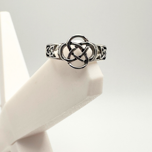 Silver Celtic knot ring on a white mannequin hand against a light gray background