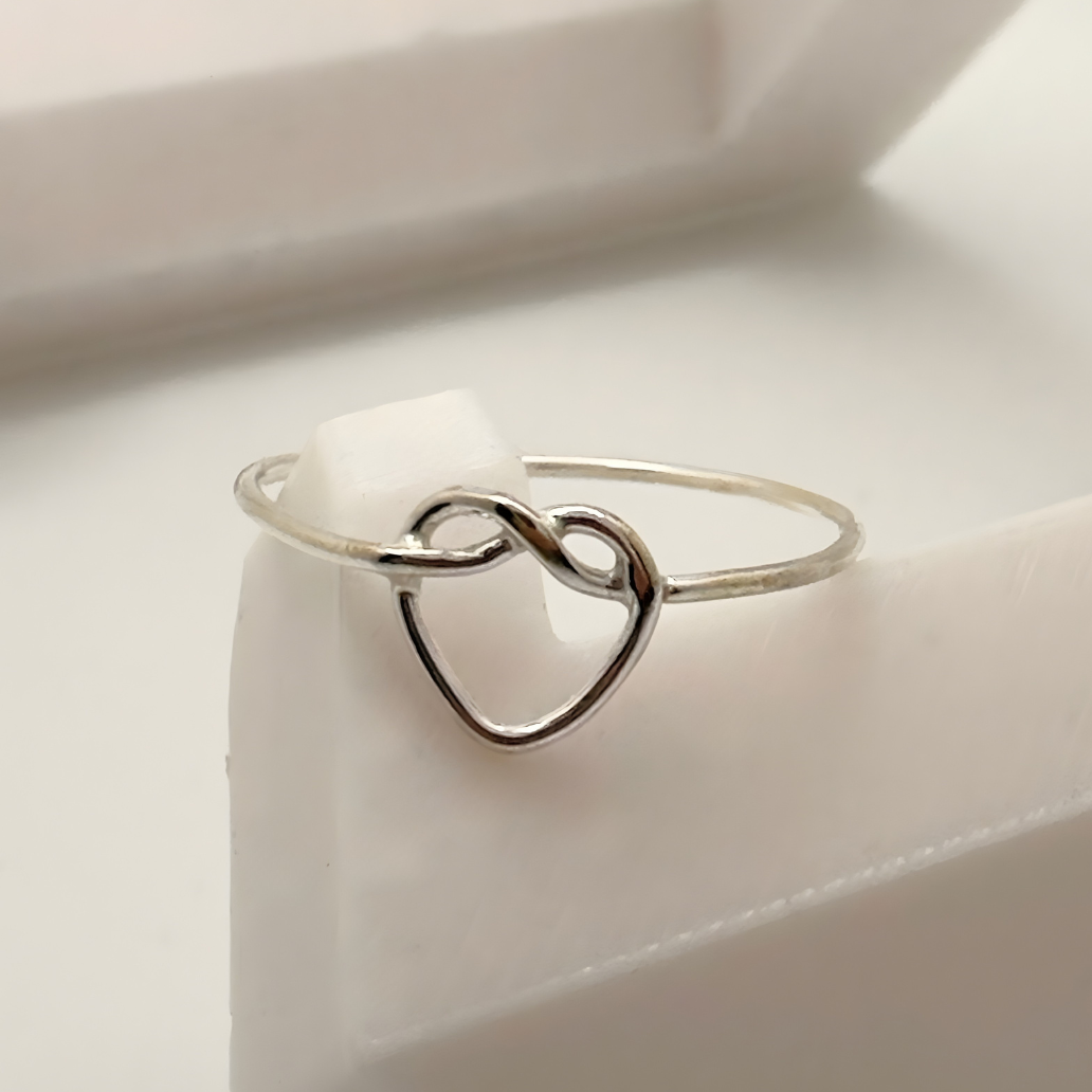 Silver heart-shaped ring on a white surface