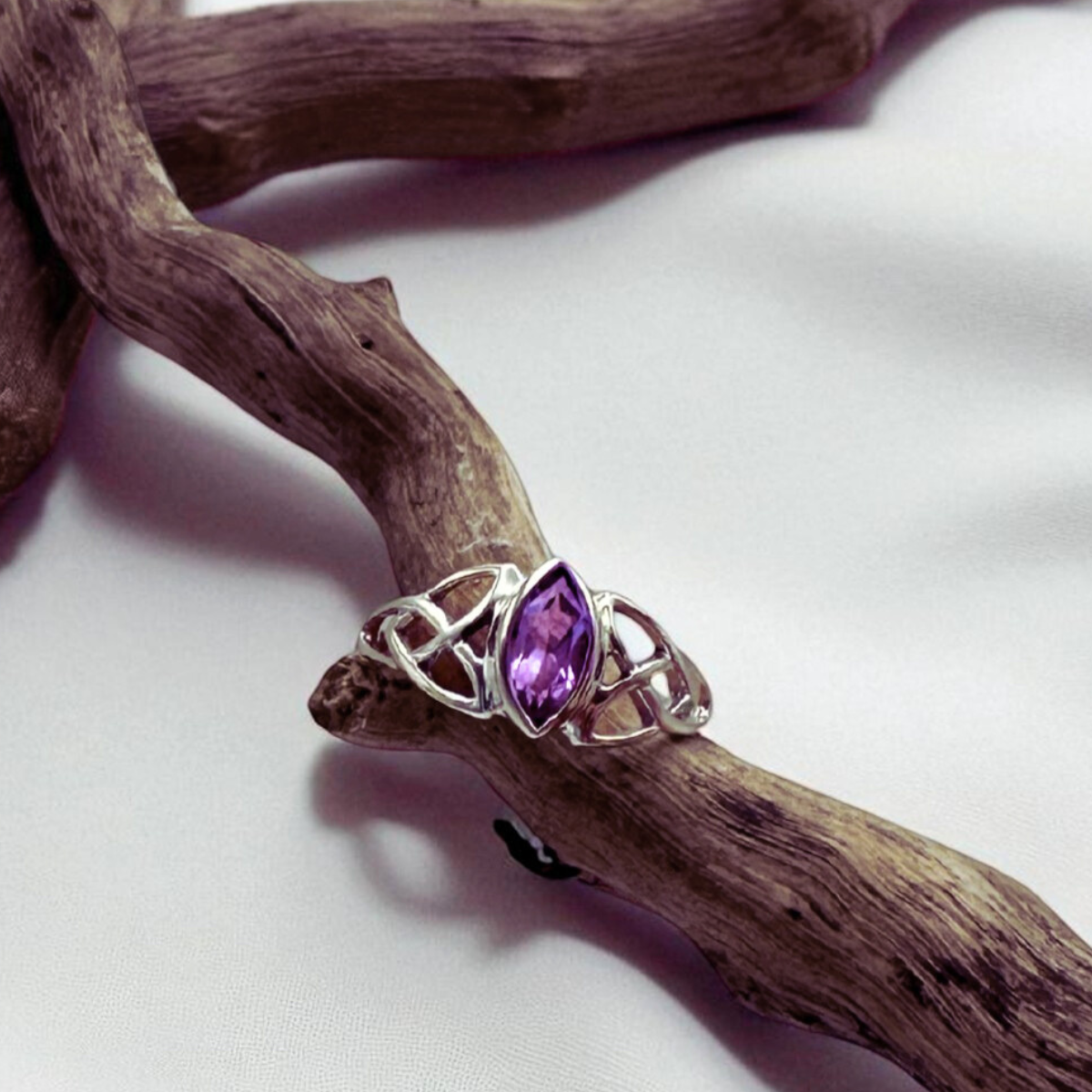 Silver ring with a purple gemstone on a wooden branch