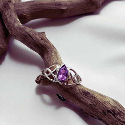 Silver ring with a purple gemstone on a wooden branch