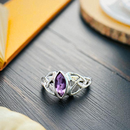 Silver ring with an amethyst gemstone on a wooden surface
